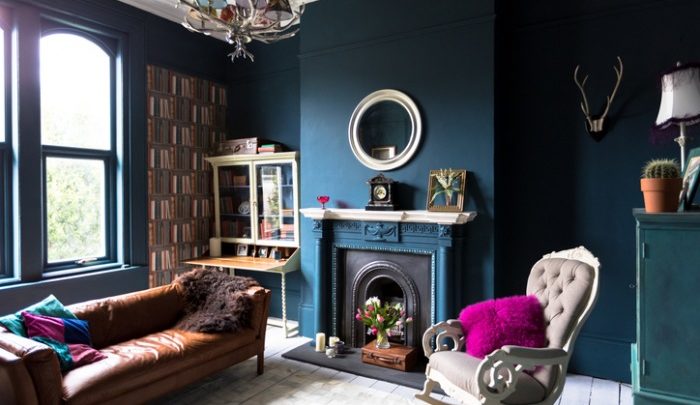 A vintage inspired living room with a blue wall and a leather couch
